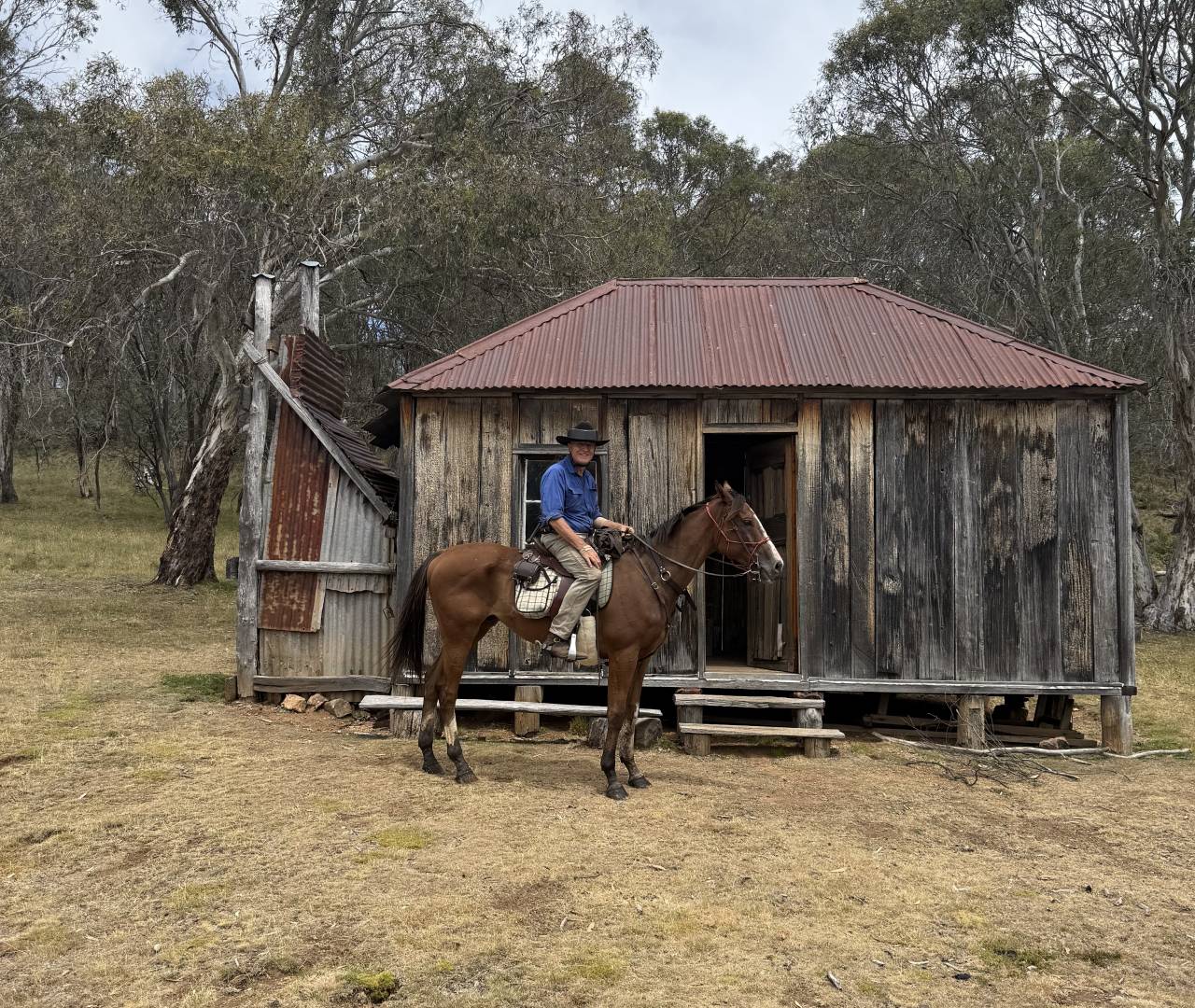 Cowboy on horse outside rustic wooden cabin